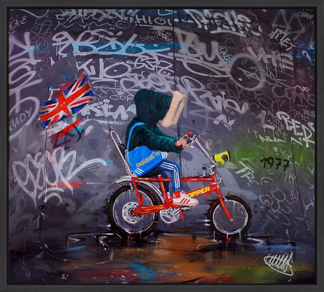 Limited edition framed hand finished canvas print of the original painting “Chopper 77 Graffiti” by Wild Seeley — gritty nostalgic British street scene with a hooded rider on a bright red Raleigh Chopper bike at night, Union Jack flag flying behind, Adidas blue bag, Adidas trainers, moody grey-black sky with a glowing moon and splashes of spray-paint energy.