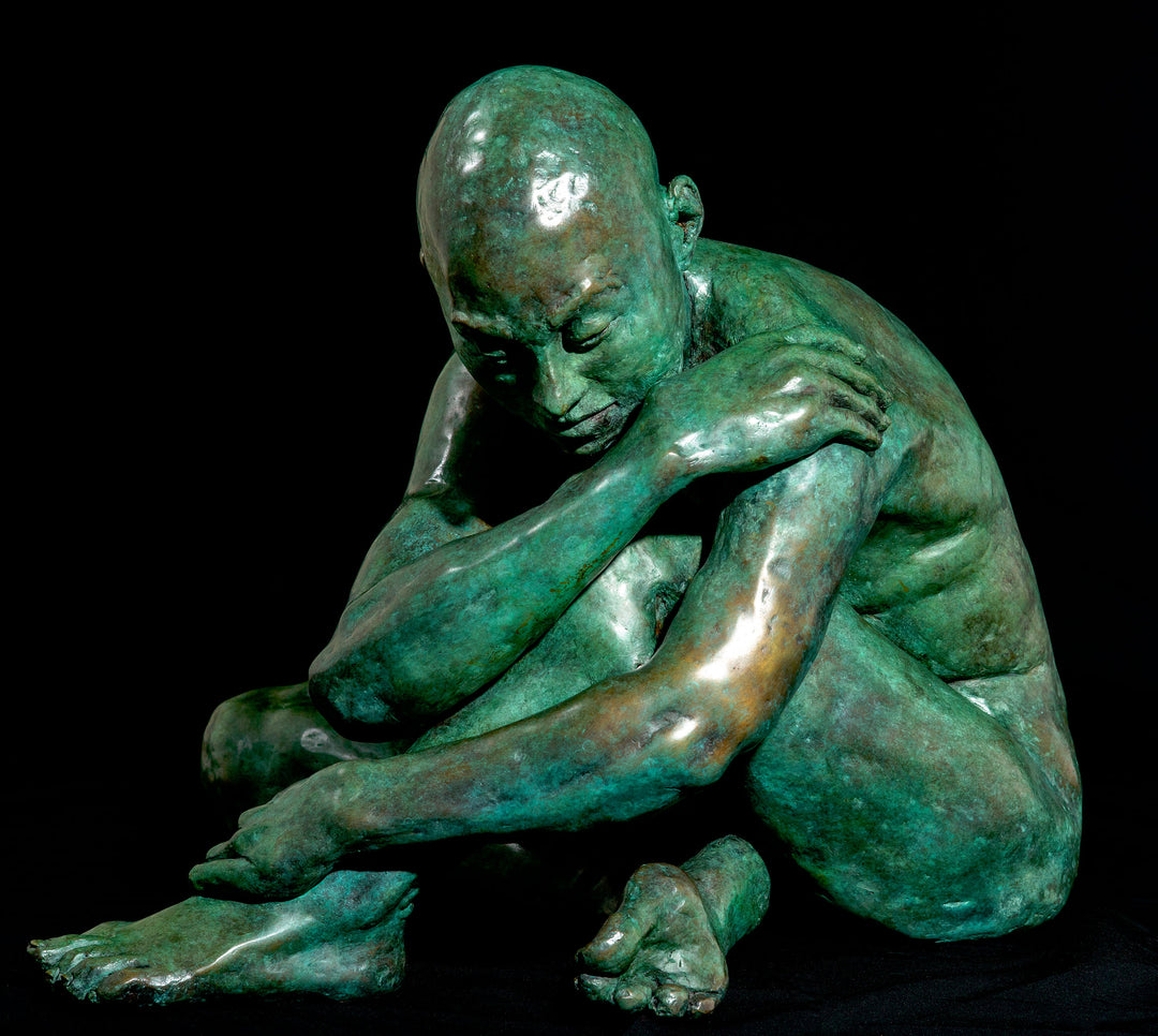 Teresa Wells’ Loss (2021), limited edition bronze sculpture, depicting a seated, nude male figure with shaved head, arms wrapped around knees in a pose of introspection and vulnerability. Finished in a rich green patina with subtle bronze undertones, the piece reveals finely modelled musculature, expressive hands and feet, and a downcast gaze. At 52cm × 42cm × 42cm and 58kg, the work conveys quiet strength and emotional depth, suitable for indoor display or sheltered outdoor placement.