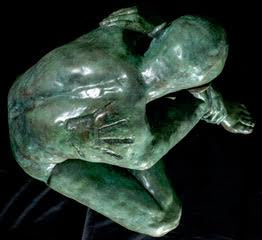 Teresa Wells’ Loss (2021), limited edition bronze sculpture, depicting a seated, nude male figure with shaved head, arms wrapped around knees in a pose of introspection and vulnerability. Finished in a rich green patina with subtle bronze undertones, the piece reveals finely modelled musculature, expressive hands and feet, and a downcast gaze. At 52cm × 42cm × 42cm and 58kg, the work conveys quiet strength and emotional depth, suitable for indoor display or sheltered outdoor placement.