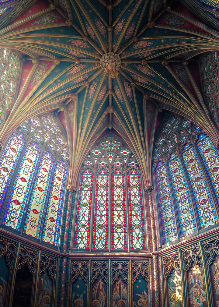 Expansive panoramic view of Ely Cathedral’s octagonal lantern tower, showing intricate stained glass, fan-vaulted roof, and painted saints, bathed in radiant light and medieval detail.