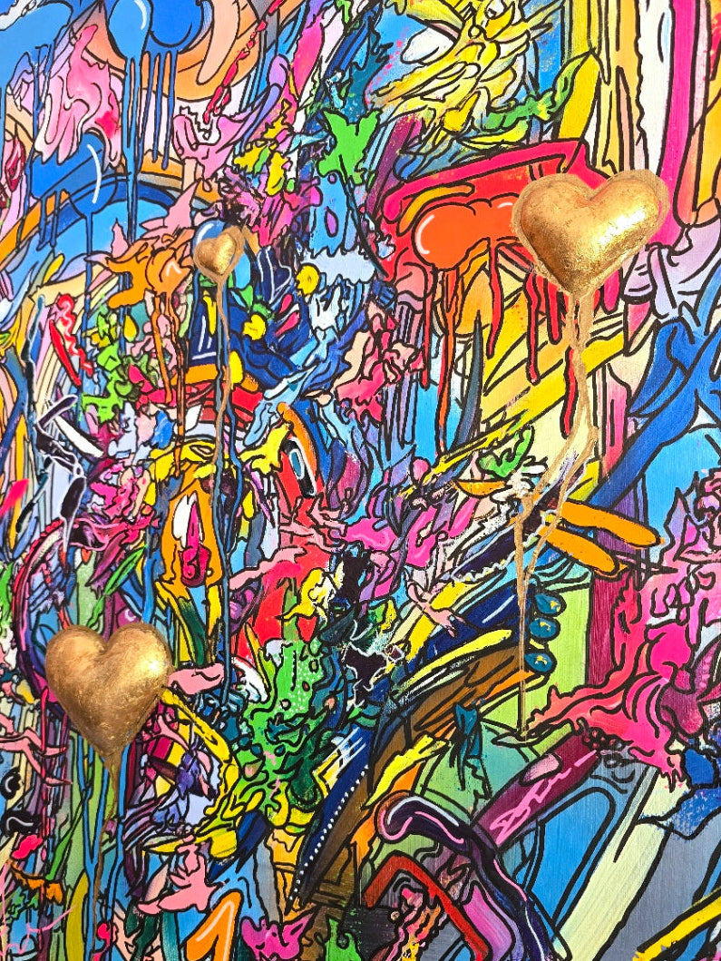A vibrant mixed-media abstract artwork filled with layered graffiti-style lines, drips and splashes in bright pinks, blues, yellows and greens, featuring three raised gold 3D heart elements floating within the composition, framed in a black tray frame.