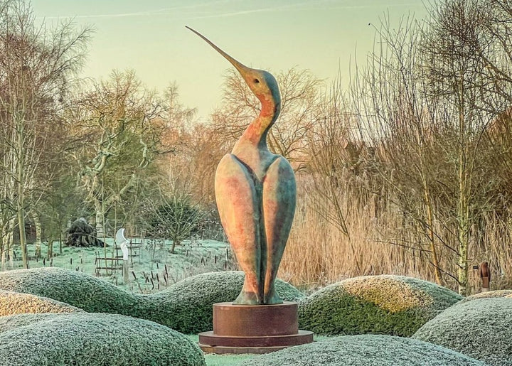 Simon Gudgeon bronze sculpture Luna featuring an elegant abstract curlew-inspired bird form with sweeping curved lines displayed within landscaped garden settings.