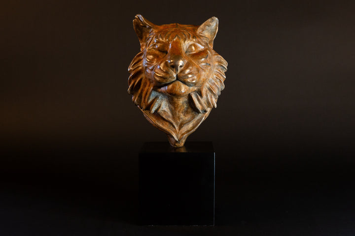 Melindungi Puna Sumatran Tiger bronze sculpture by Min Reid, serene tiger head portrait with closed eyes and flowing fur detail in warm golden bronze tones mounted on a black plinth against a dark background