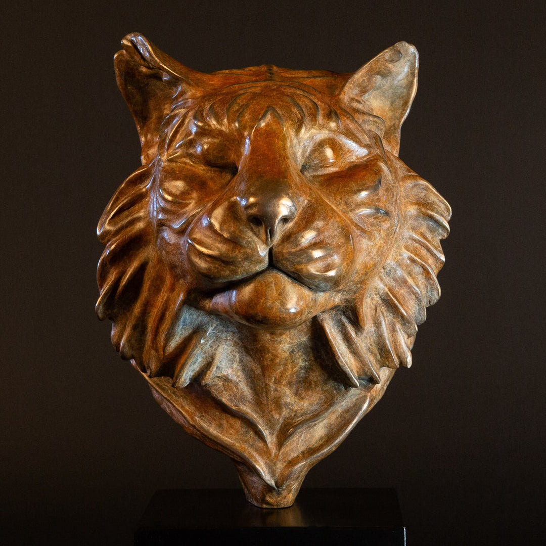Melindungi Puna Sumatran Tiger bronze sculpture by Min Reid, serene tiger head portrait with closed eyes and flowing fur detail in warm golden bronze tones mounted on a black plinth against a dark background