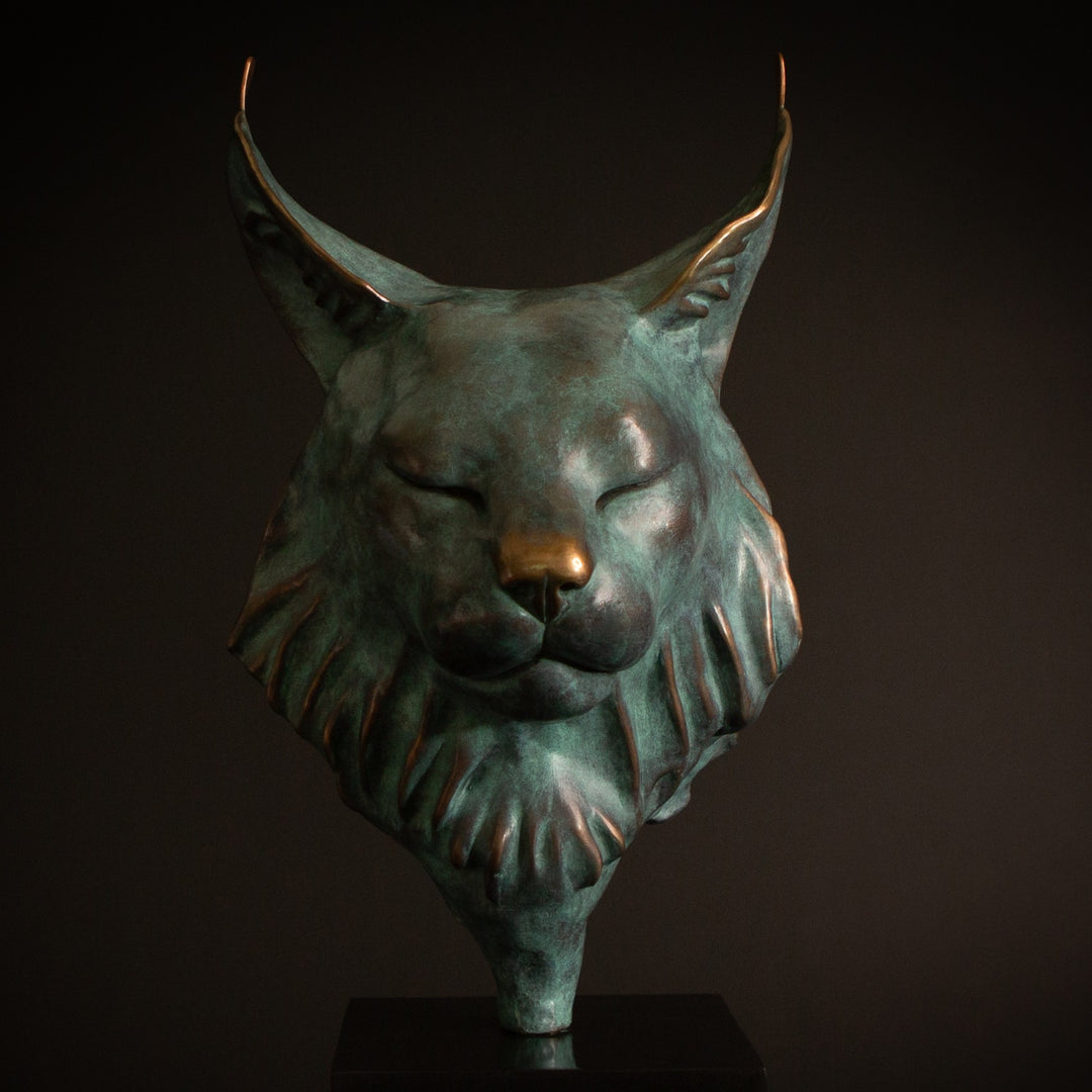 Petra Eurasian Lynx bronze sculpture by Min Reid, serene lynx head with closed eyes and pointed ear tufts in green verdigris bronze with warm copper highlights, mounted on a black plinth, contemporary wildlife bronze sculpture