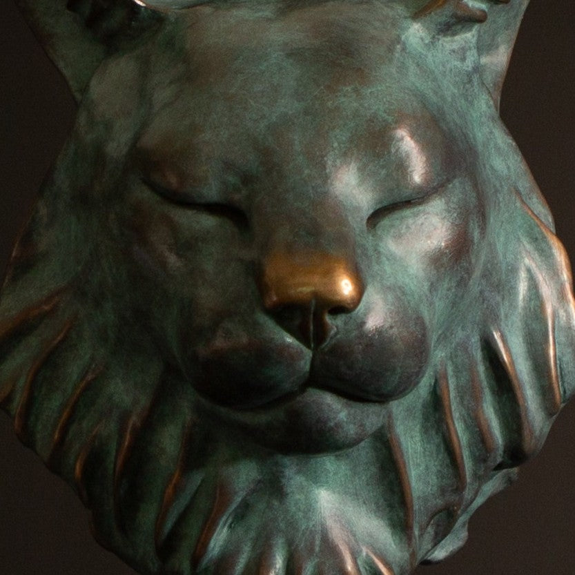 Petra Eurasian Lynx bronze sculpture by Min Reid, serene lynx head with closed eyes and pointed ear tufts in green verdigris bronze with warm copper highlights, mounted on a black plinth, contemporary wildlife bronze sculpture