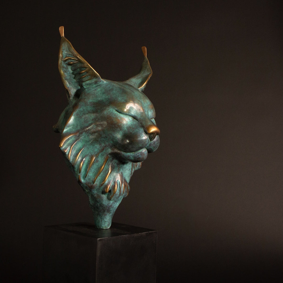 Petra Eurasian Lynx bronze sculpture by Min Reid, serene lynx head with closed eyes and pointed ear tufts in green verdigris bronze with warm copper highlights, mounted on a black plinth, contemporary wildlife bronze sculpture