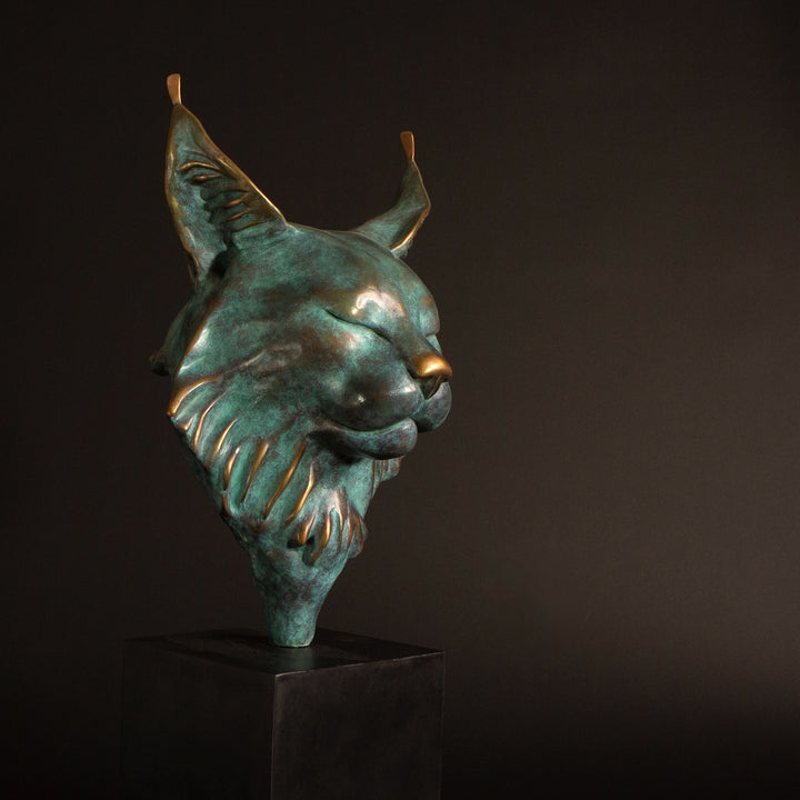 Petra Eurasian Lynx bronze sculpture by Min Reid, serene lynx head with closed eyes and pointed ear tufts in green verdigris bronze with warm copper highlights, mounted on a black plinth, contemporary wildlife bronze sculpture