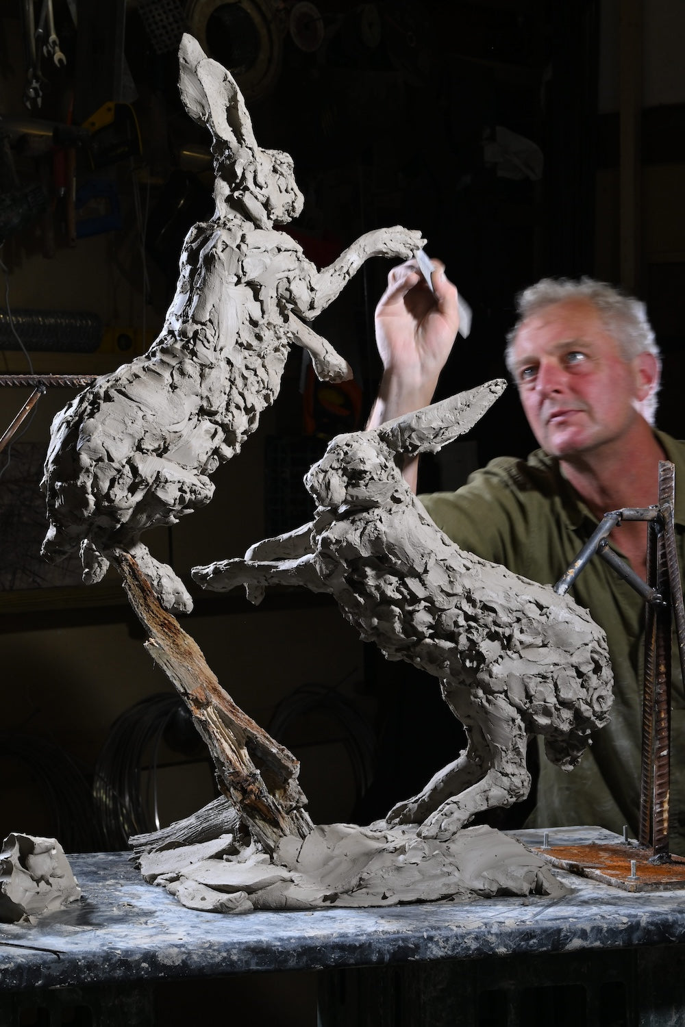 ‘Boxing Hares’ by Hamish Mackie, a limited-edition bronze wildlife sculpture depicting two hares leaping and boxing in mid-air during their characteristic springtime courtship behaviour. The dynamic composition captures their extended limbs, twisting bodies and expressive movement, with richly textured surfaces that convey the energy of the original hand-modelled clay. Photograph shows the original clay sculpture prior to bronze casting.