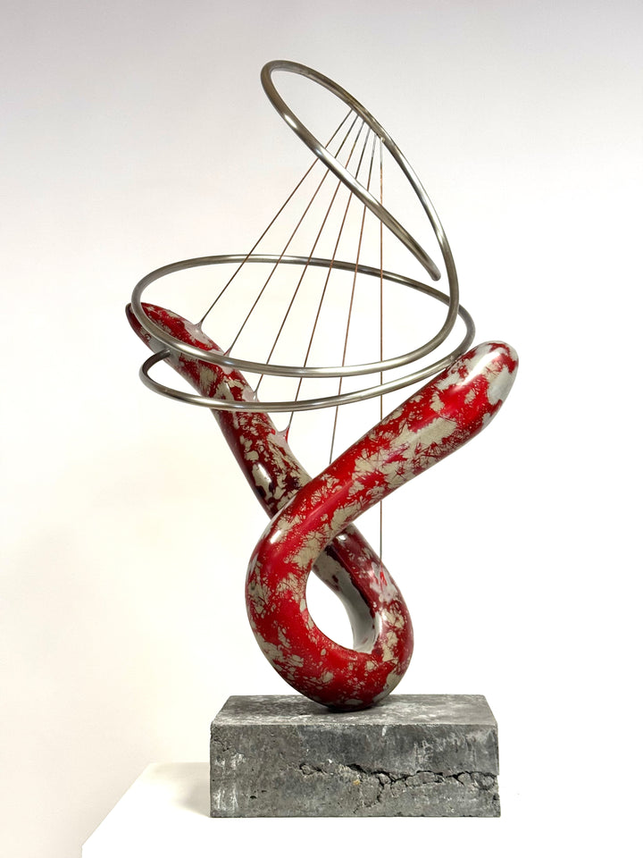 Abstract mixed media sculpture with looping red and silver marbled GRP form, intersected by brushed stainless steel rings and fine rust-treated steel strands, mounted on a grey stone base. Contemporary one-off artwork by Mark Purllant.