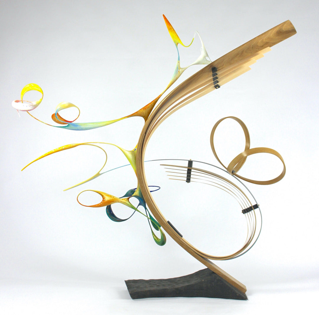Freedom by Mark Purllant, an award-winning one-off mixed media sculpture in carved and steam-bent English oak with painted sculptural forms, maple veneer, ebony, and brass details, mounted on a scorched oak base with flowing, dynamic curves in yellow, blue, orange, and green.