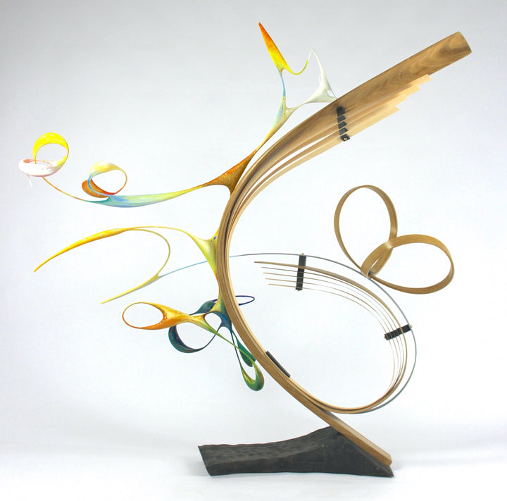 Freedom by Mark Purllant, an award-winning one-off mixed media sculpture in carved and steam-bent English oak with painted sculptural forms, maple veneer, ebony, and brass details, mounted on a scorched oak base with flowing, dynamic curves in yellow, blue, orange, and green.