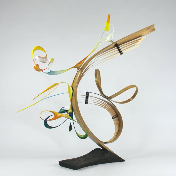 Freedom by Mark Purllant, an award-winning one-off mixed media sculpture in carved and steam-bent English oak with painted sculptural forms, maple veneer, ebony, and brass details, mounted on a scorched oak base with flowing, dynamic curves in yellow, blue, orange, and green.
