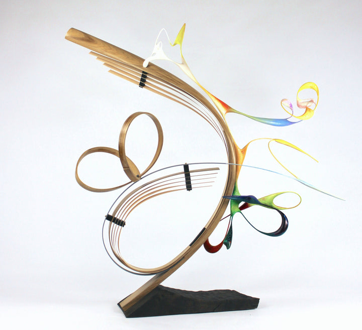 Freedom by Mark Purllant, an award-winning one-off mixed media sculpture in carved and steam-bent English oak with painted sculptural forms, maple veneer, ebony, and brass details, mounted on a scorched oak base with flowing, dynamic curves in yellow, blue, orange, and green.