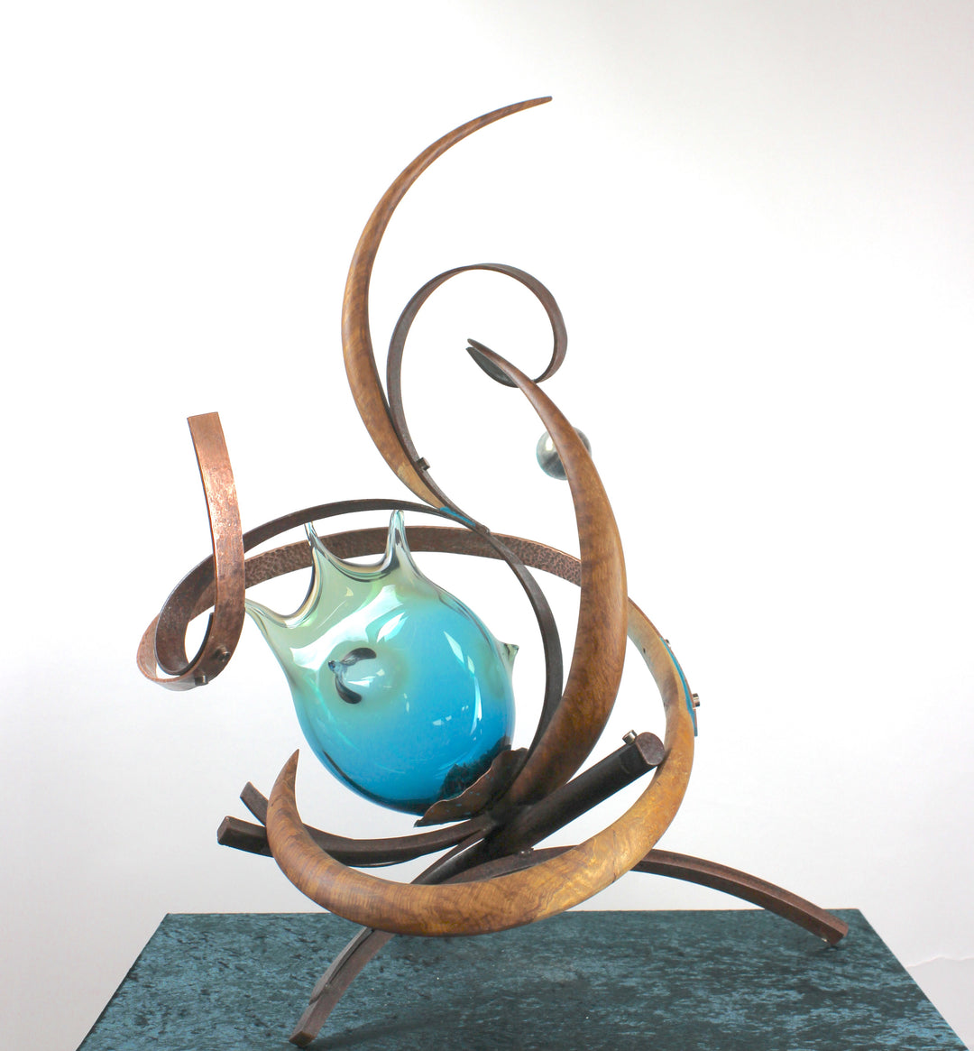 Pod by Mark Purllant, a one-off mixed media sculpture combining carved English brown oak, rust-treated steel, and hand-blown glass in vivid sea green and blue tones, accented with hand-beaten copper and organic flowing forms.