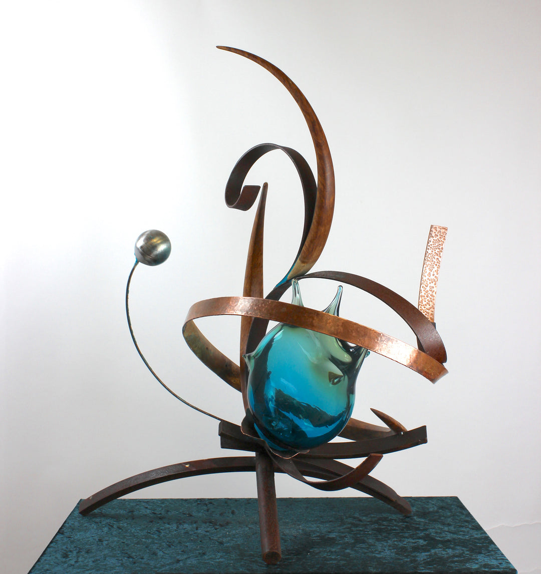 Pod by Mark Purllant, a one-off mixed media sculpture combining carved English brown oak, rust-treated steel, and hand-blown glass in vivid sea green and blue tones, accented with hand-beaten copper and organic flowing forms.