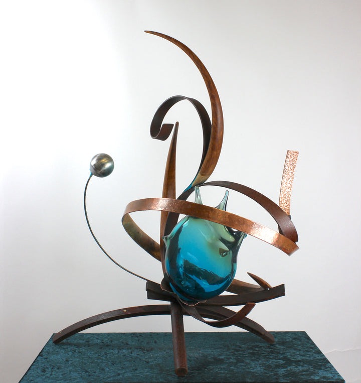 Pod by Mark Purllant, a one-off mixed media sculpture combining carved English brown oak, rust-treated steel, and hand-blown glass in vivid sea green and blue tones, accented with hand-beaten copper and organic flowing forms.