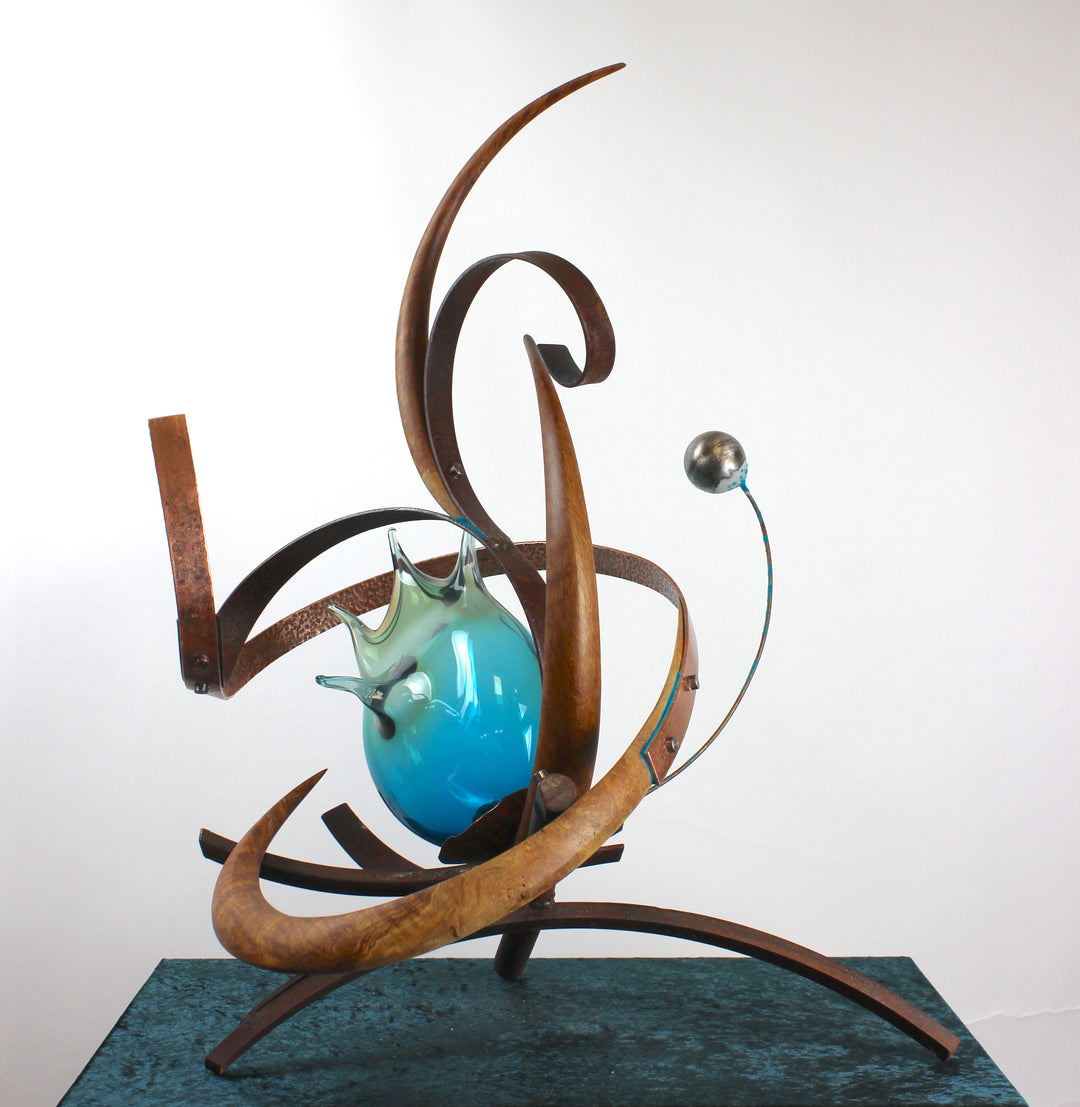 Pod by Mark Purllant, a one-off mixed media sculpture combining carved English brown oak, rust-treated steel, and hand-blown glass in vivid sea green and blue tones, accented with hand-beaten copper and organic flowing forms.