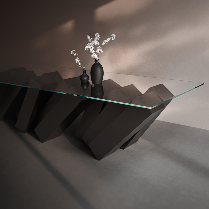 Duffy London Megalith Dining Table with angled black monolithic base and clear glass top, creating a gravity-defying illusion of collapsing architectural forms.