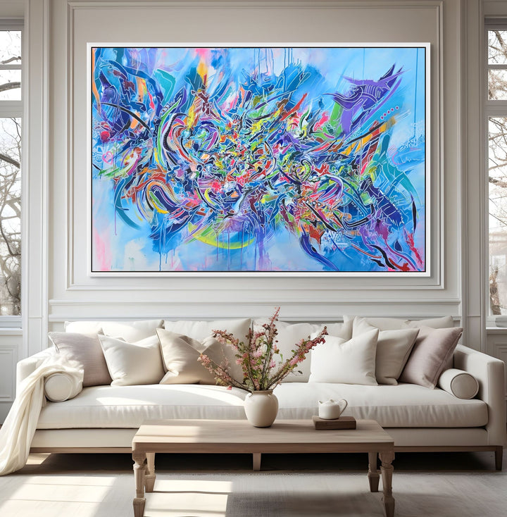 Vibrant large-scale abstract graffiti painting bursting with layered colour, bold sweeping lines and dynamic shapes against a bright blue background, framed in a white tray frame.