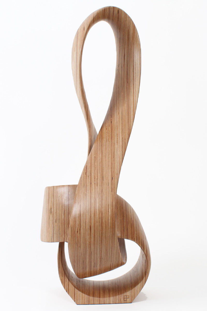 Hand-carved birch plywood sculpture by Bill Prickett combining a treble clef and Möbius strip into a continuous, flowing form, with layered wood grain revealing an infinity loop inspired by music and mathematics.