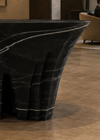 Duffy London Monument Valley Dining Table carved from marble with sculptural canyon-like base and glass top, inspired by natural rock formations.