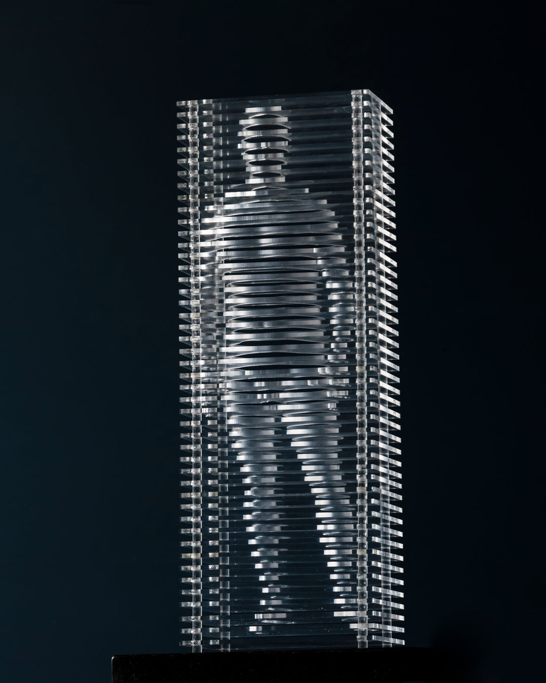 Layered acrylic sculpture by Tom Hiscox featuring a standing human figure formed from precision-cut transparent slices, encased within a rectangular structure and mounted on a polished granite base.