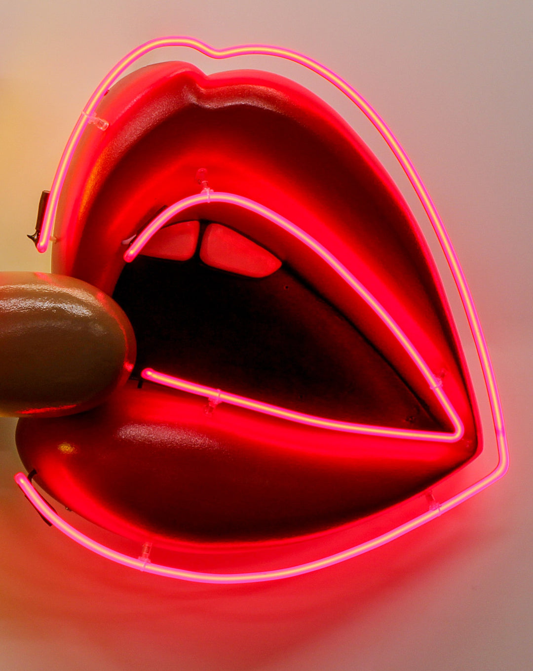 Playful neon wall art by Chris Bracey featuring a hot dog with the words “HOT Licks” in glowing yellow and pink neon, paired with a bold red neon mouth and lips design. Sculptural elements include a fabricated hot dog and 3D lips, combining humour and innuendo in classic Bracey style.