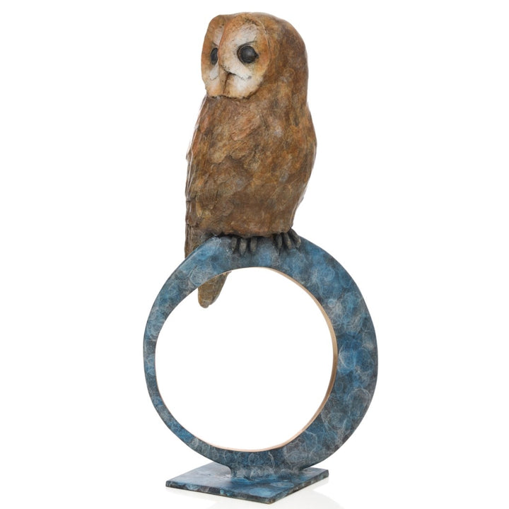 ‘Nocturne’ by Pat Bull, a limited-edition contemporary bronze wildlife sculpture depicting a tawny owl perched on top of a large upright circular bronze ring. The owl features a rounded, heart-shaped facial disc in cream and warm beige, prominent dark eyes and detailed feathers finished in earthy brown and bronze tones. The open ring features a mottled turquoise, teal and blue-green patina with a contrasting polished golden inner edge, mounted on a small rectangular bronze base against a white background.