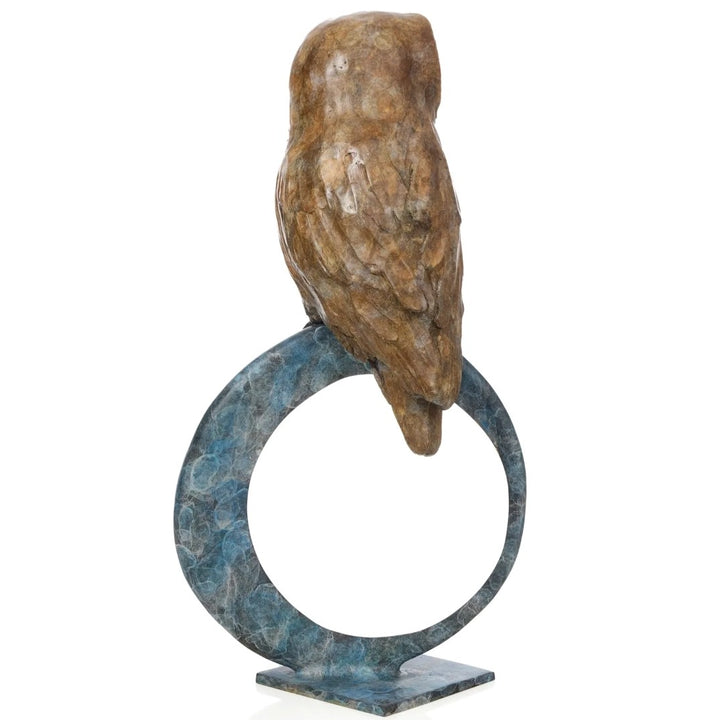 ‘Nocturne’ by Pat Bull, a limited-edition contemporary bronze wildlife sculpture depicting a tawny owl perched on top of a large upright circular bronze ring. The owl features a rounded, heart-shaped facial disc in cream and warm beige, prominent dark eyes and detailed feathers finished in earthy brown and bronze tones. The open ring features a mottled turquoise, teal and blue-green patina with a contrasting polished golden inner edge, mounted on a small rectangular bronze base against a white background.