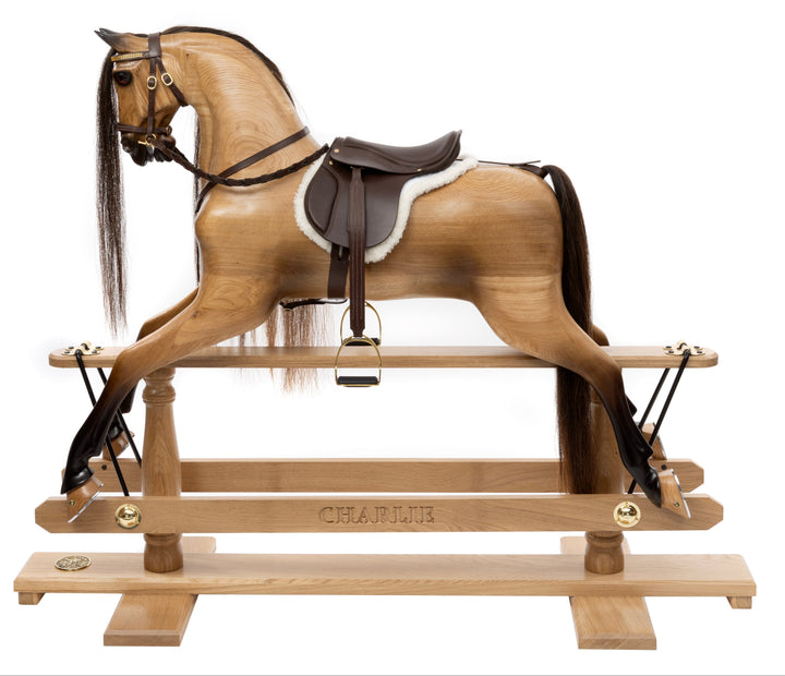 Hand-carved wooden rocking horse with leather saddle, set in a traditional living room with characterful decor.
