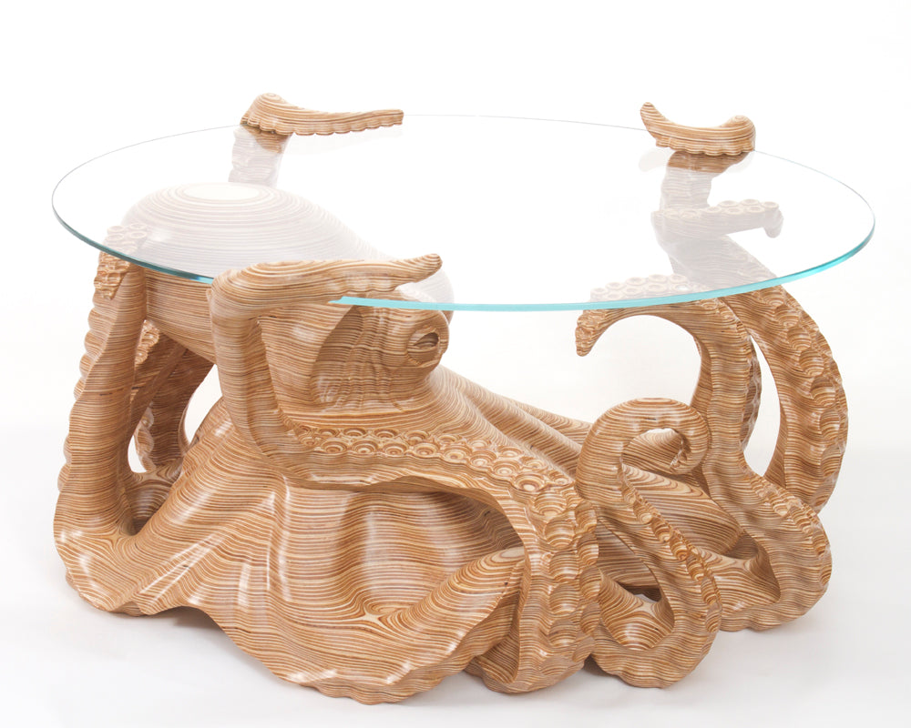 Hand-carved birch plywood octopus coffee table by Bill Prickett with sculptural tentacles supporting a low iron toughened glass top, combining functional furniture with detailed contemporary wood sculpture.