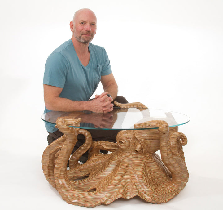 Hand-carved birch plywood octopus coffee table by Bill Prickett with sculptural tentacles supporting a low iron toughened glass top, combining functional furniture with detailed contemporary wood sculpture.