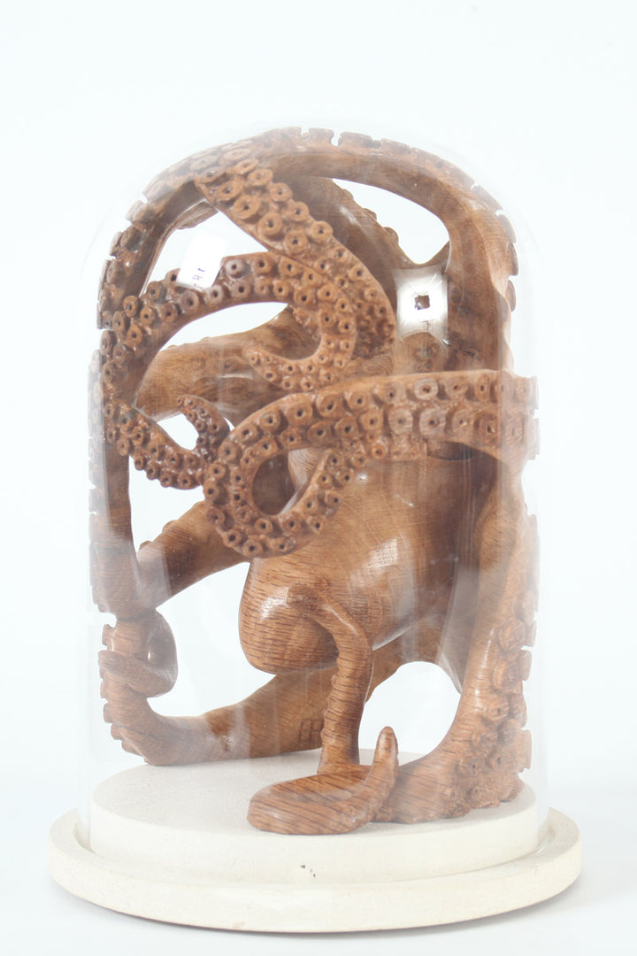 Hand-carved wooden octopus sculpture by Bill Prickett, carved from English oak burr and enclosed within a clear glass dome, its detailed tentacles pressed against the curved surface and mounted on a Portland stone base.