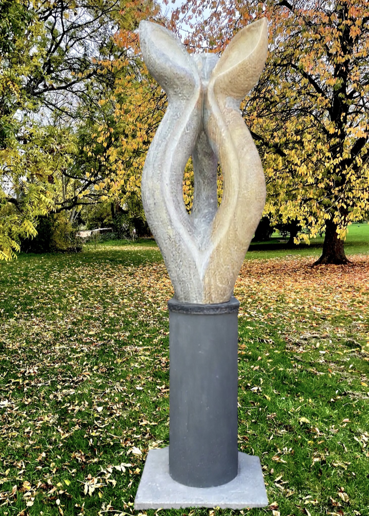 Offspring by Martin Cash — a hand-carved Ancaster Weatherbed stone sculpture mounted on a granite base. The tall, abstract form features two intertwined organic shapes, symbolising growth and unity, designed for display in gardens or public spaces.
