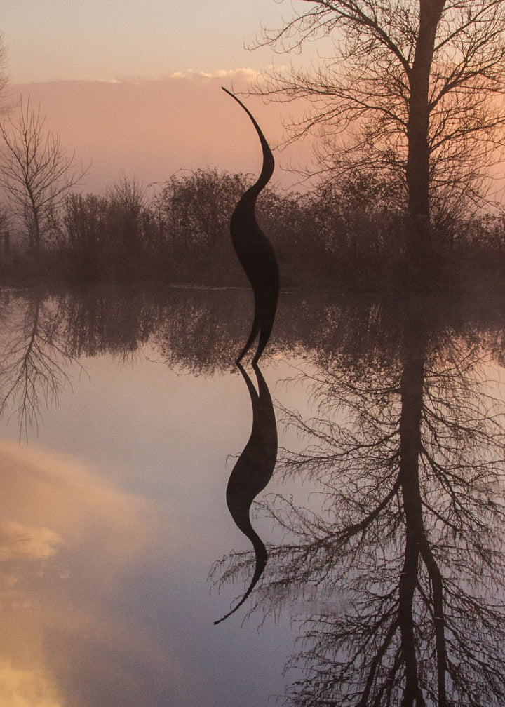 Simon Gudgeon bronze sculpture Origins featuring a tall abstract organic bird-inspired form with elegant flowing curves displayed within a landscaped outdoor setting.