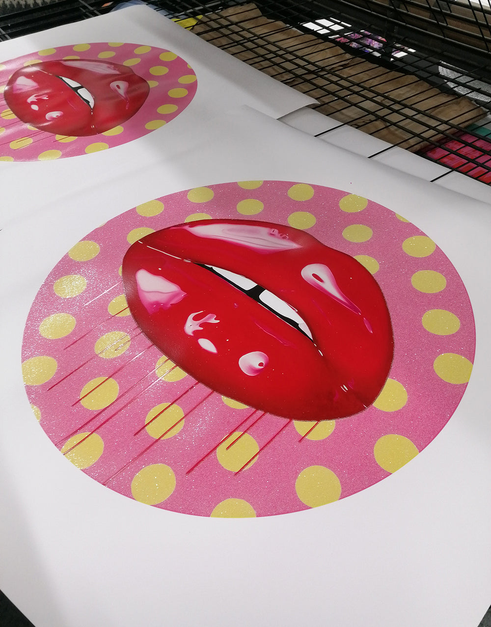 Glossy hot pink lips with dripping paint on a pink and yellow polka dot background.
