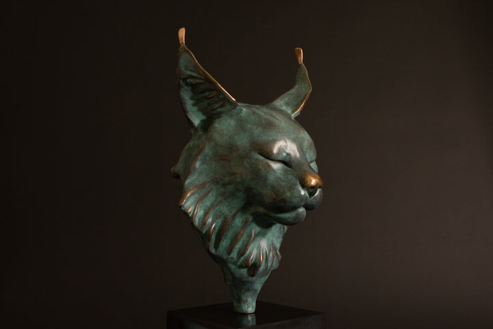 Petra Eurasian Lynx bronze sculpture by Min Reid, serene lynx head with closed eyes and pointed ear tufts in green verdigris bronze with warm copper highlights, mounted on a black plinth, contemporary wildlife bronze sculpture