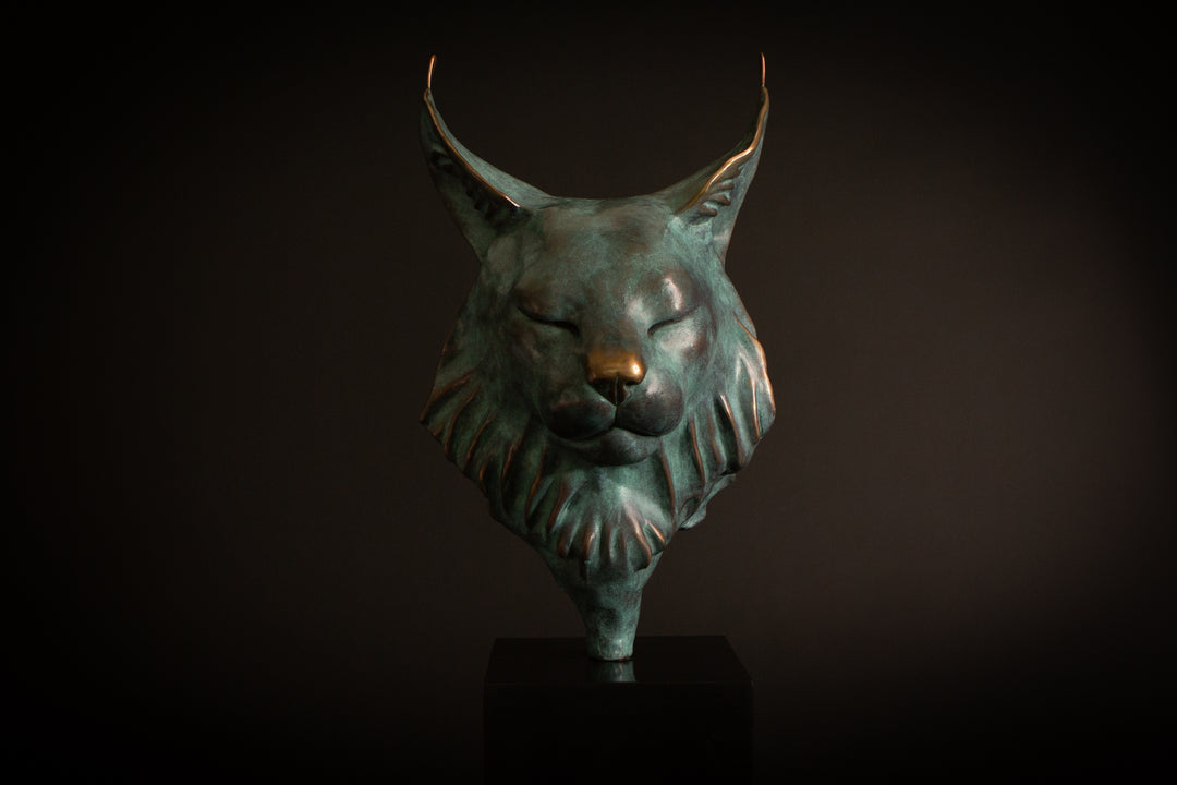Petra Eurasian Lynx bronze sculpture by Min Reid, serene lynx head with closed eyes and pointed ear tufts in green verdigris bronze with warm copper highlights, mounted on a black plinth, contemporary wildlife bronze sculpture