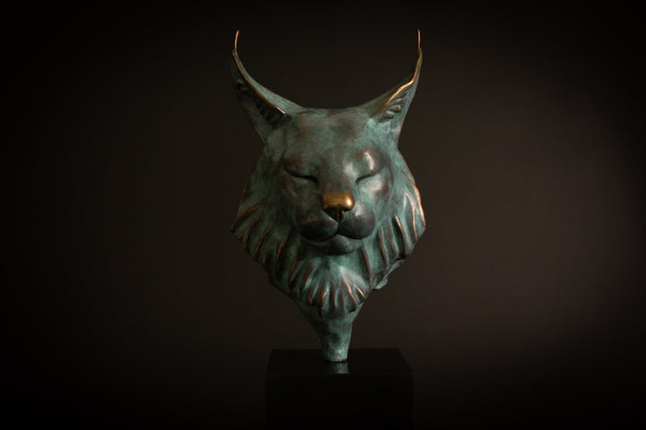 Petra Eurasian Lynx bronze sculpture by Min Reid, serene lynx head with closed eyes and pointed ear tufts in green verdigris bronze with warm copper highlights, mounted on a black plinth, contemporary wildlife bronze sculpture