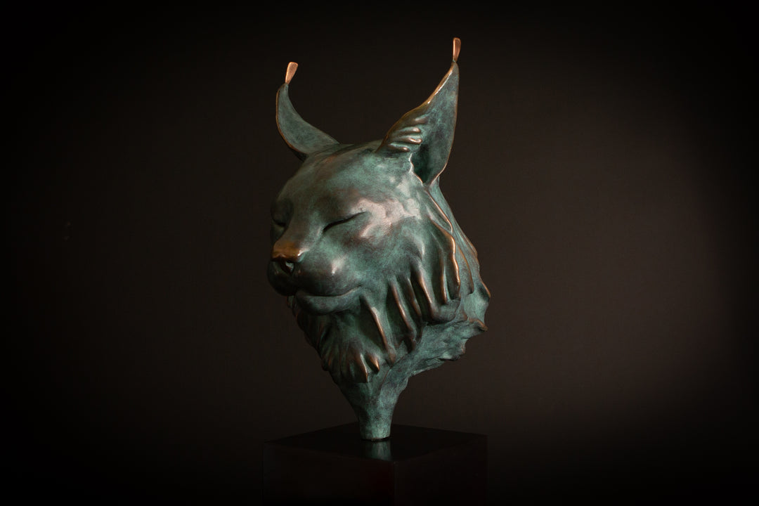 Petra Eurasian Lynx bronze sculpture by Min Reid, serene lynx head with closed eyes and pointed ear tufts in green verdigris bronze with warm copper highlights, mounted on a black plinth, contemporary wildlife bronze sculpture