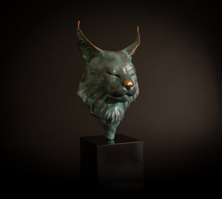 Petra Eurasian Lynx bronze sculpture by Min Reid, serene lynx head with closed eyes and pointed ear tufts in green verdigris bronze with warm copper highlights, mounted on a black plinth, contemporary wildlife bronze sculpture
