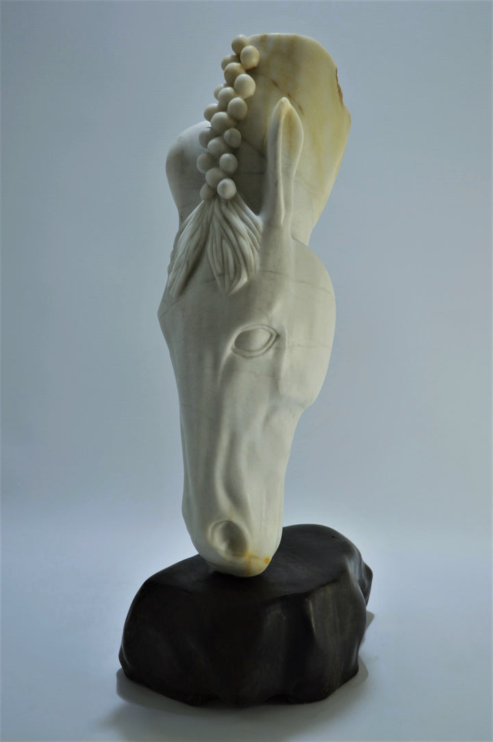 Deborah Harrison sculpture Palomo, a one-off hand-carved horse head in rainbow alabaster with intricate mane detail and a natural crown of rounded alabaster spheres, mounted on a dark soapstone base. The alabaster reveals soft white, ivory, cream and golden brown tones with darker natural veining, blending realism with symbolic form.