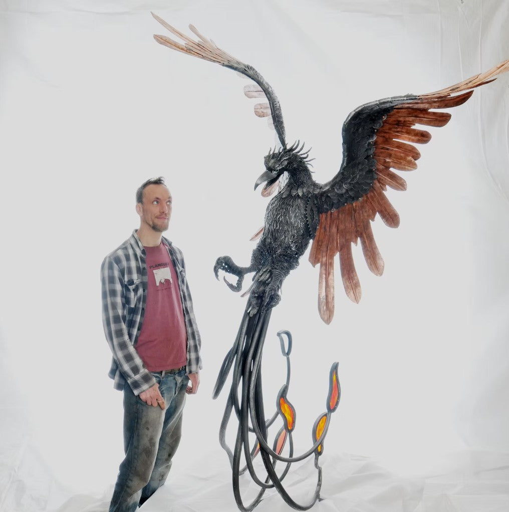 Winged steampunk Phoenix sculpture crafted from reclaimed metal with mechanical detailing and flowing tentacle-like elements.