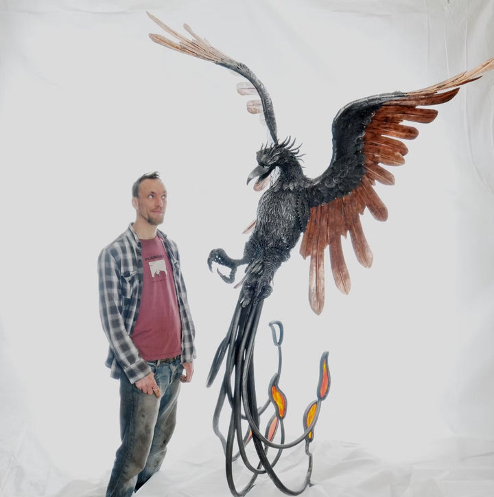 Winged steampunk Phoenix sculpture crafted from reclaimed metal with mechanical detailing and flowing tentacle-like elements.