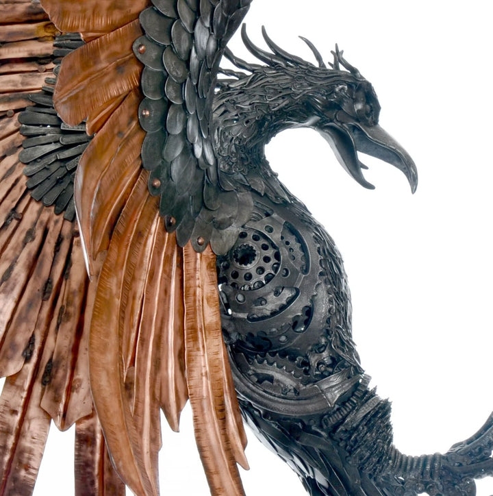 Winged steampunk Phoenix sculpture crafted from reclaimed metal with mechanical detailing and flowing tentacle-like elements.