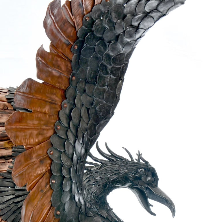 Winged steampunk Phoenix sculpture crafted from reclaimed metal with mechanical detailing and flowing tentacle-like elements.