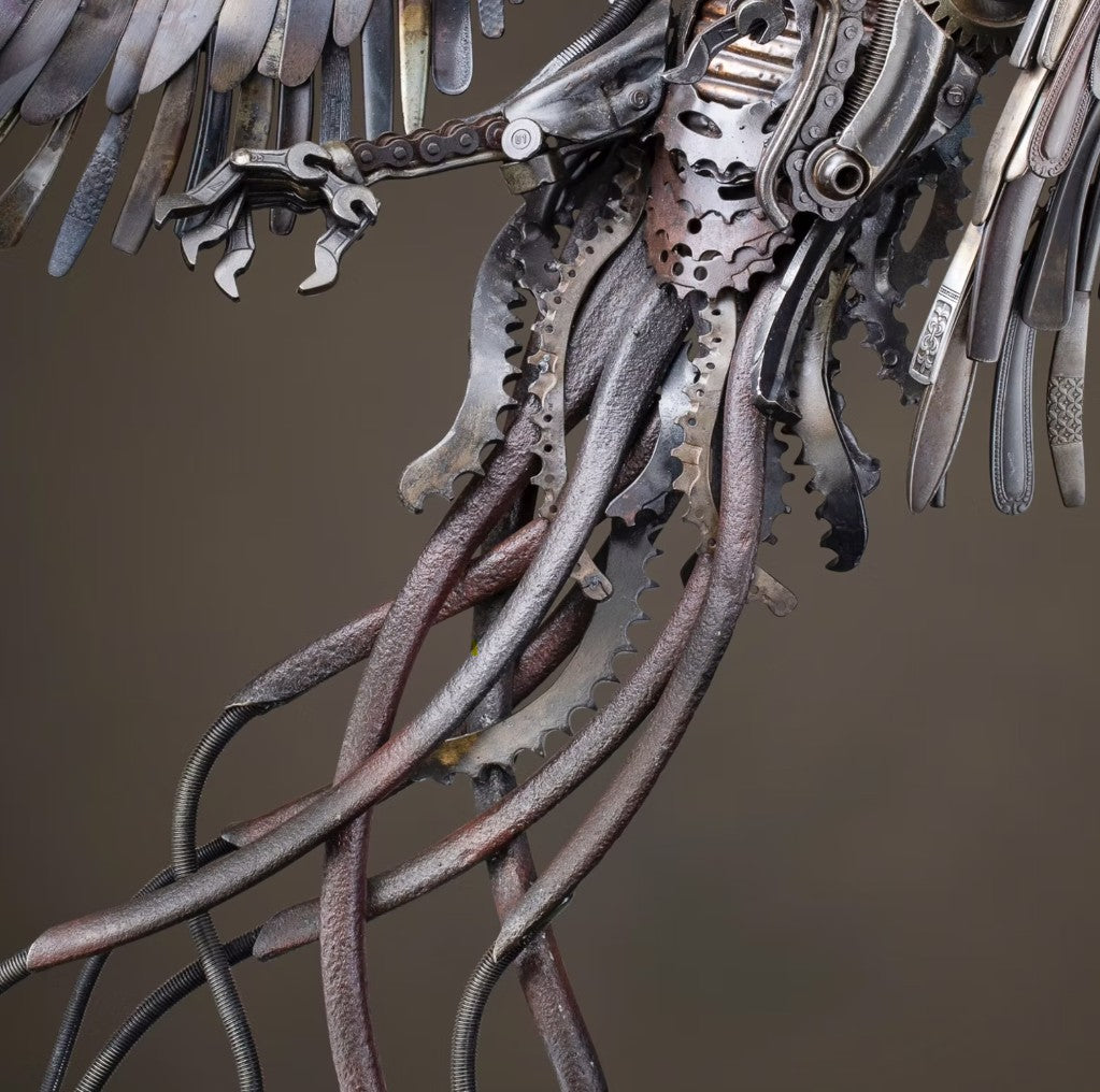 Winged steampunk Phoenix sculpture crafted from reclaimed metal with mechanical detailing and flowing tentacle-like elements.