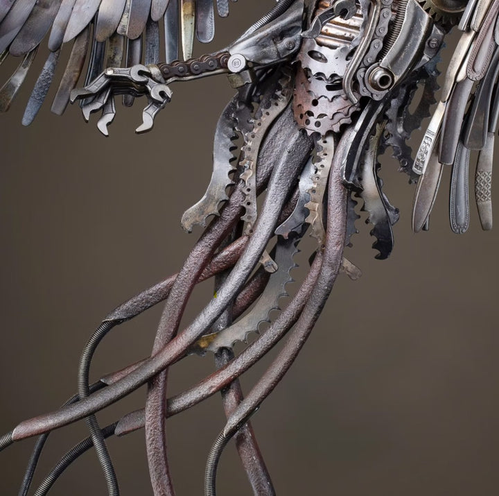Winged steampunk Phoenix sculpture crafted from reclaimed metal with mechanical detailing and flowing tentacle-like elements.