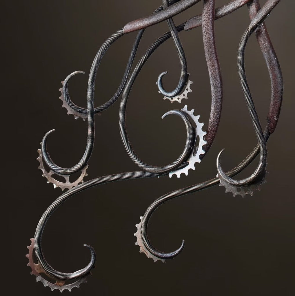 Winged steampunk Phoenix sculpture crafted from reclaimed metal with mechanical detailing and flowing tentacle-like elements.